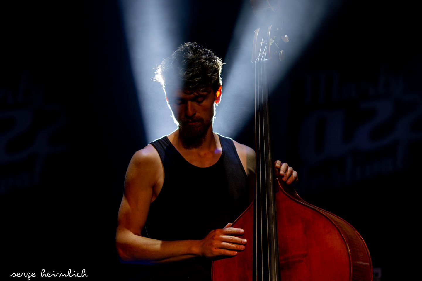  Une photo de Julien Moneret sur scène lors d'un concert, sous les projecteurs, tenant sa contrebasse, par Serge Heimlich. 